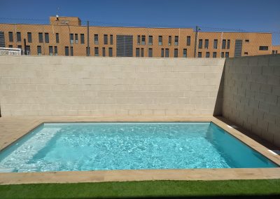 Piscina de obra con escalera integrada y césped artificial